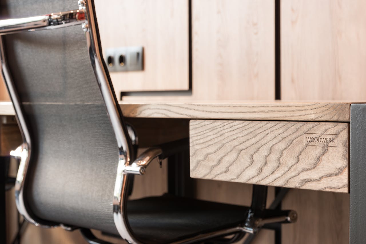 Creative design of wooden table with wavy lines and armchair against wall in contemporary workspace